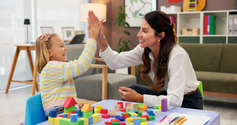 A child high-fiving her allied health therapist during a play-based therapy session
