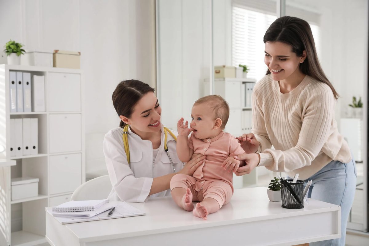 A paediatrician checking a happy baby while the mother looks on, at Berwick Paediatric & Family Specialists